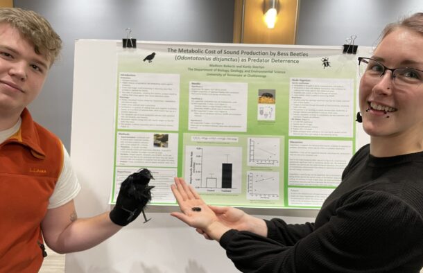 Kurtis Stechyn wears Hanes the crow on his hand and Madison Roberts holds a Bess Beetle, two elements in their animal physiology research project.
