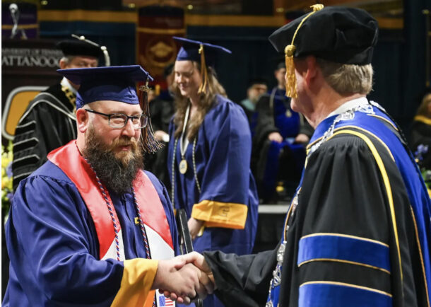Brad Crush, left, shakes hands with Chancellor Steve Angle during UTC undergraduate commencement ceremonies. Crush, a member of the U.S. Marines from 2012-2016, received a bachelor’s degree in history.