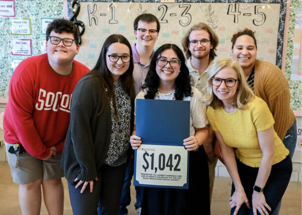 Music students Collin Sutton, Emily Bruce, Christian Cantrell, Bradley Bee and Remington Prado-Bonner and Associate Professor Ali Allerton (yellow top) surround DuPont Elementary School music teacher Lauren Cardenas after presenting her with a gift of $1,042 for school supplies.