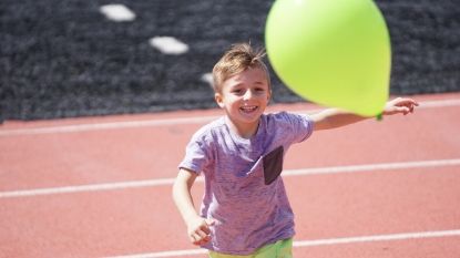 a small boy playing with a green balloon