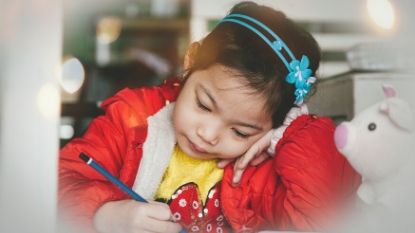 a young girl drawing with a pencil