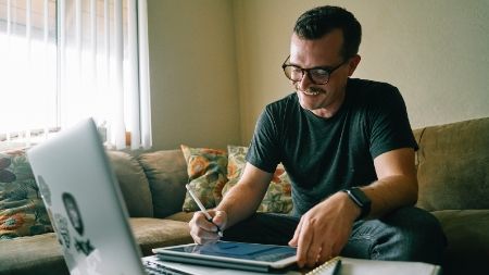 man working on his laptop and iPad from home