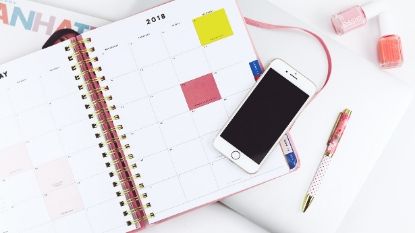 white iPhone and planner on a desk 