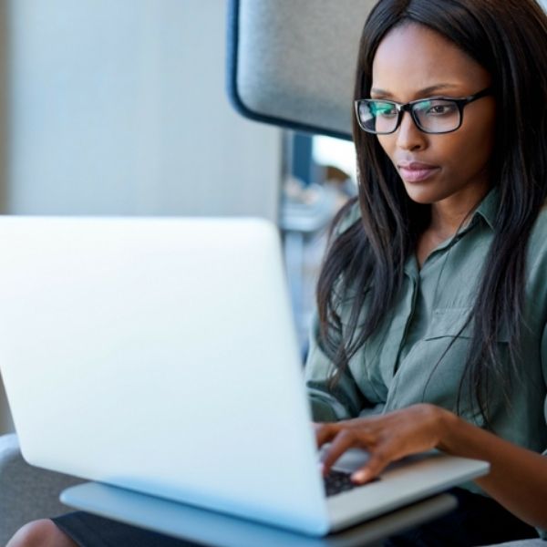 African-American female typing on a white laptop