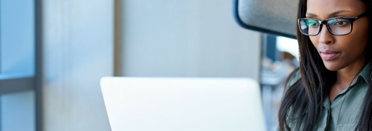 African-American female typing on a white laptop