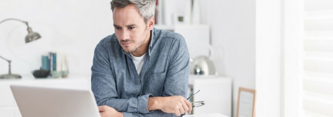 man looking at white laptop
