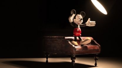 Mickey Mouse standing on top of a piano with a spotlight on him