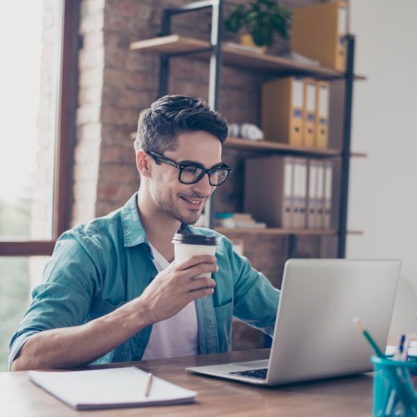 man drinking coffee and looking at his laptop