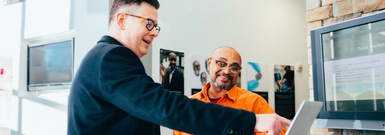 two men looking at a laptop in an office