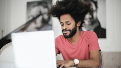 man smiling while typing on his laptop