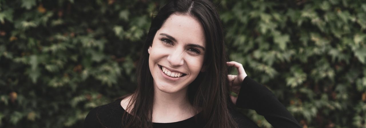 woman smiling in front of greenery