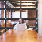 woman staring at a laptop intently in an office by herself