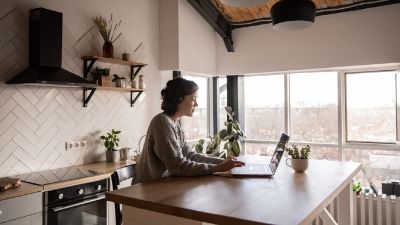 woman working on a laptop sitting at her kitchen island countertop