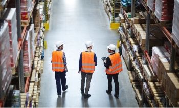 3 men wearing construction gear walking through a warehouse
