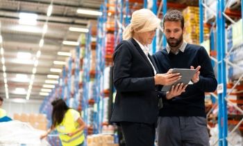 businessman and businesswoman looking at a tablet in a warehouse