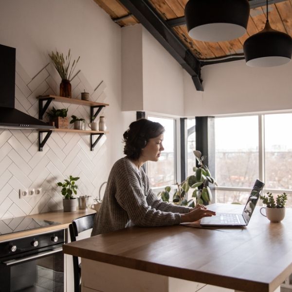 young woman typing on a laptop in her kitchen