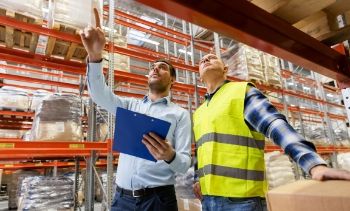 man in construction gear and man in business wear walking through a warehouse