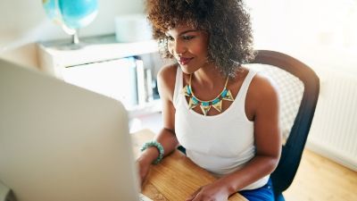 young woman smiling and typing on her laptop