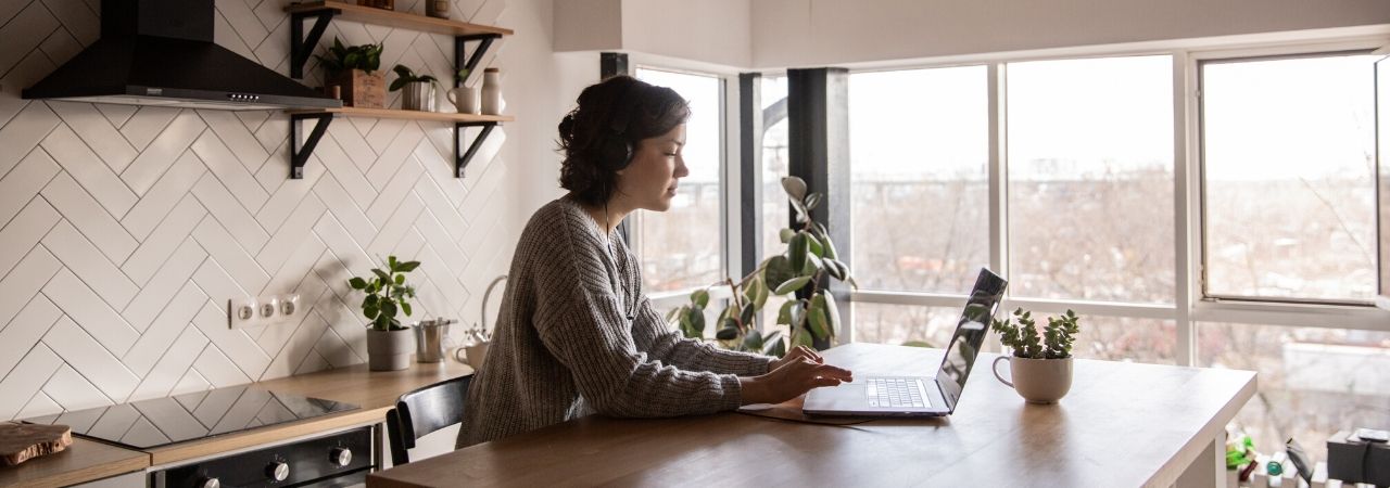 young woman typing on a laptop in her kitchen
