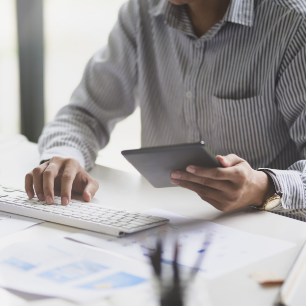 man using tablet and typing on computer keyboard