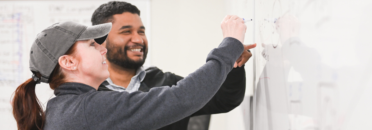 female and male student working on whiteboard together
