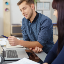 male freight broker talking to coworker while pointing at his laptop