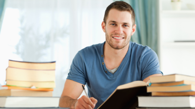 male student smiling and working in textbooks