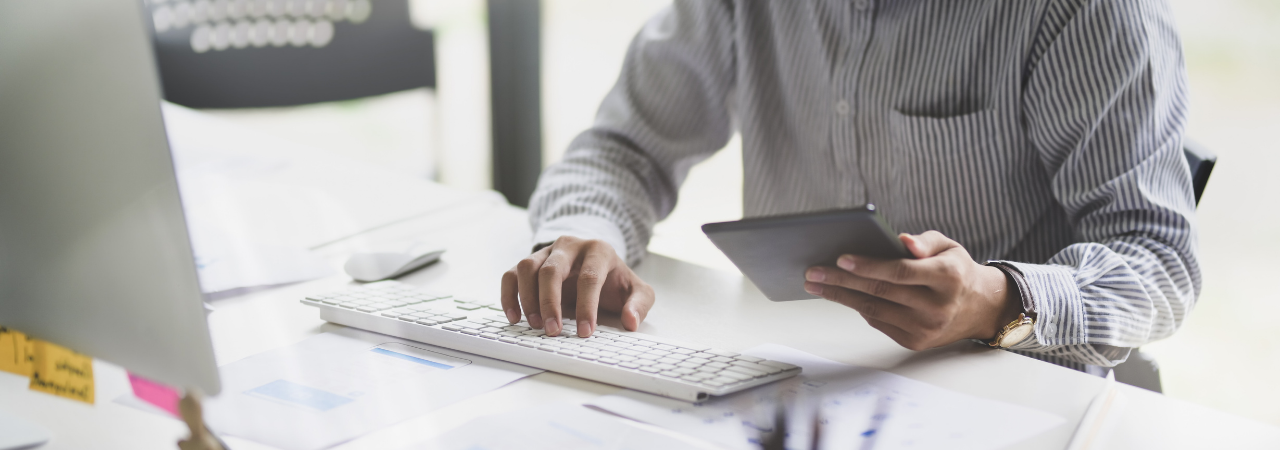 man using tablet and typing on computer keyboard