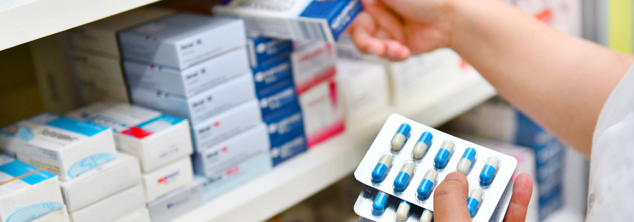 pharmacist holding pills and stocking shelves