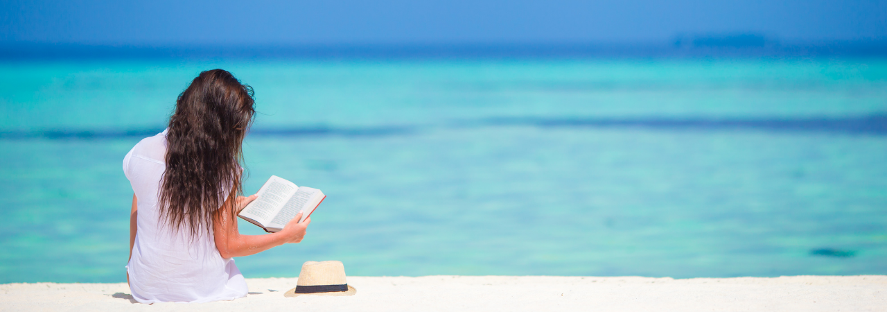 woman reading a book on the beach