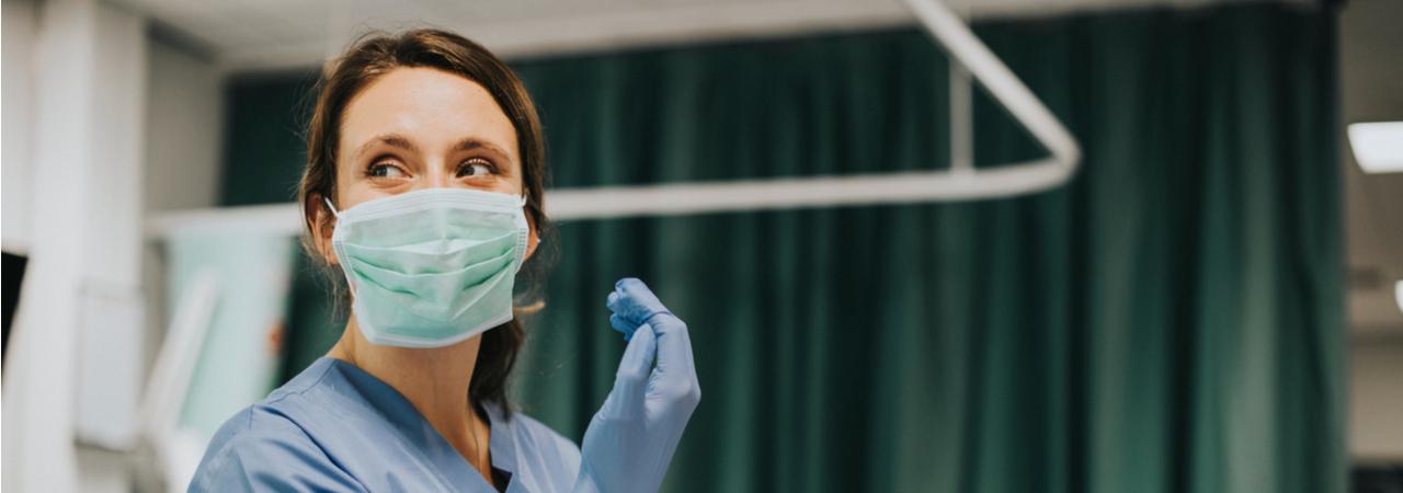 nurse wearing mask and putting on gloves