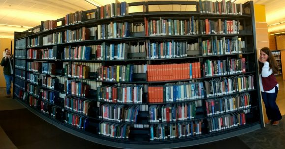 Sydney and Casey see each other from opposite ends of a book shelf