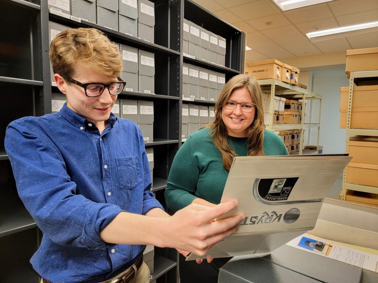 Archivists Noah Lasley and Carolyn Runyon looking at materials in the Krystal records and memorabilia collection in the Special Collections stacks.