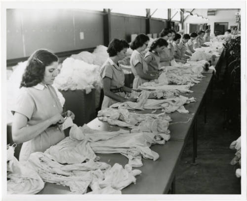 Black-and-white photograph of unidentified employees working at tables inside of the Signal Knitting Mills.