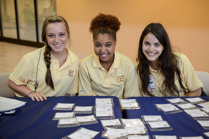 3 girls manning name badge table at Freshman Orientation