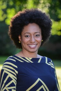Shewanee Howard-Baptiste, posing for a headshot with a lovely smile, in a fantastic blue-and-gold dress.