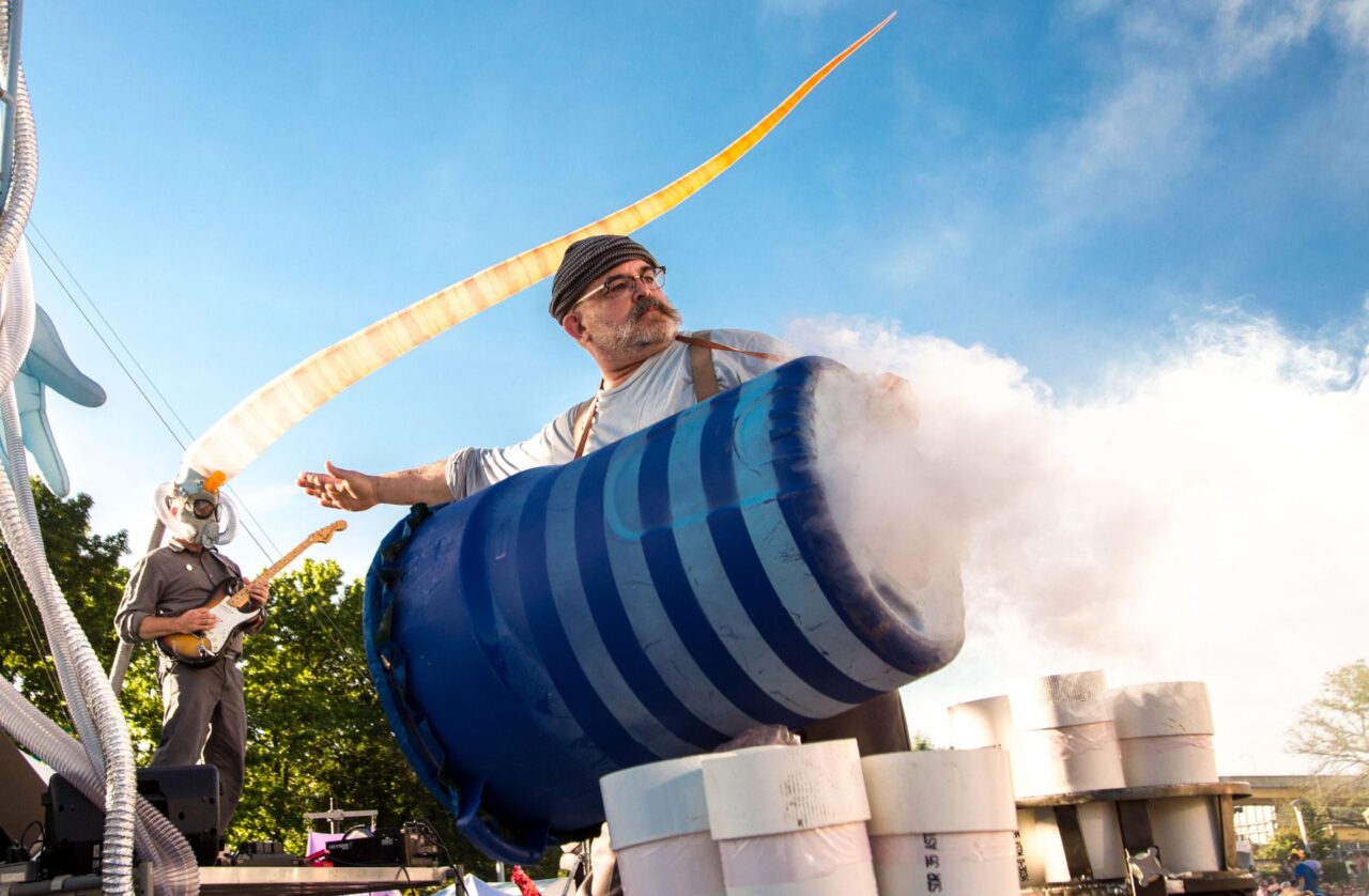 Man on stage behind smoking barrel