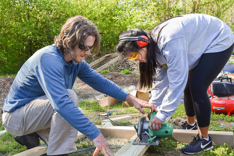 Students cutting wood to build outdoor recreation platform