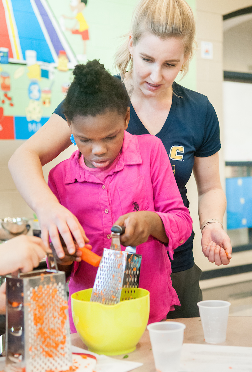 Kori Hahn helps Orchard Knob Elementary student grating carrots