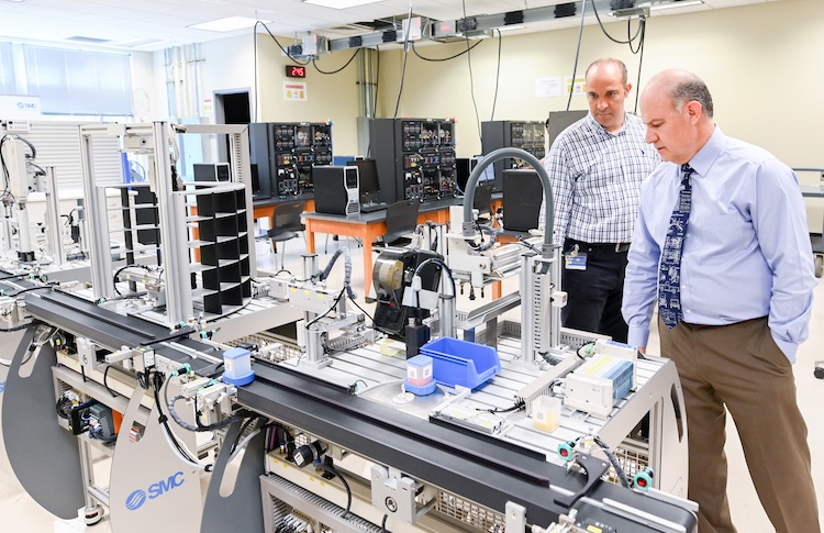 Professor Erkan Kalanoglu and Ahad Nasab, creator of the mechatronics program and department head of Engineering Management and Technology, examine the lab's production line.