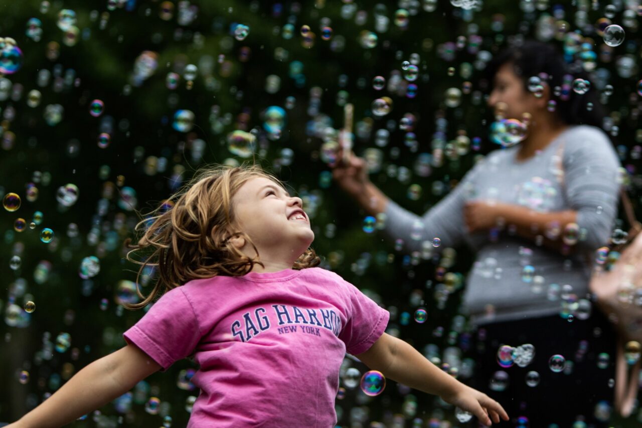 Troy Stolt photo: Molly Merbum, 6, of Ladue, Missouri, jumps up and down while playing in bubbles during the Canine Carnival in Tilles Park. Photo courtesy St. Louis Post-Dispatch.