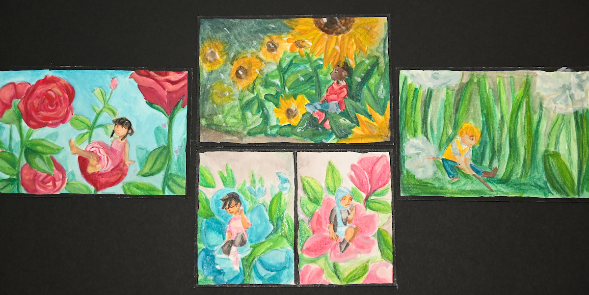Painted artworks are on small rectangular pieces of paper. The artworks depict small people sitting on flowers in a whimsical environment.