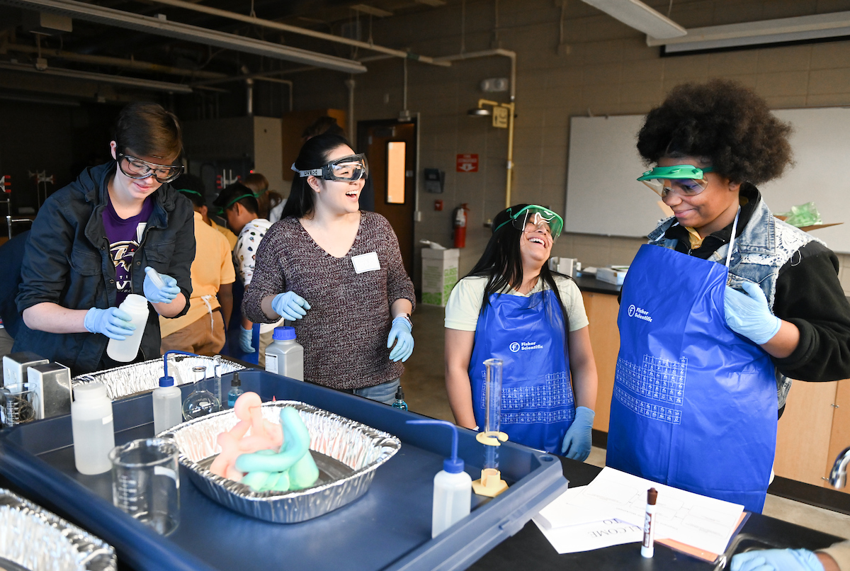 middle school and UTC students perform experiment with faom-looking substance in chemistry lab.