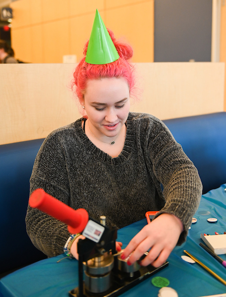 A student wearing a birthday hat makes a craft.