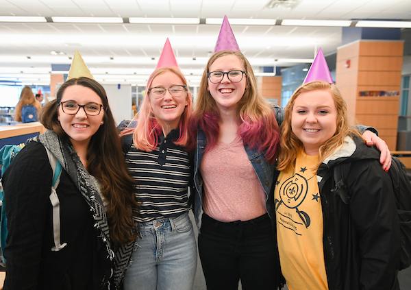 A group of students smile wearing birthday hats.