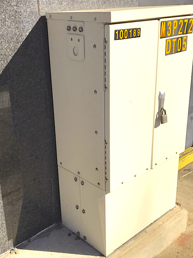 A blank electrical box is flush with a grey wall.