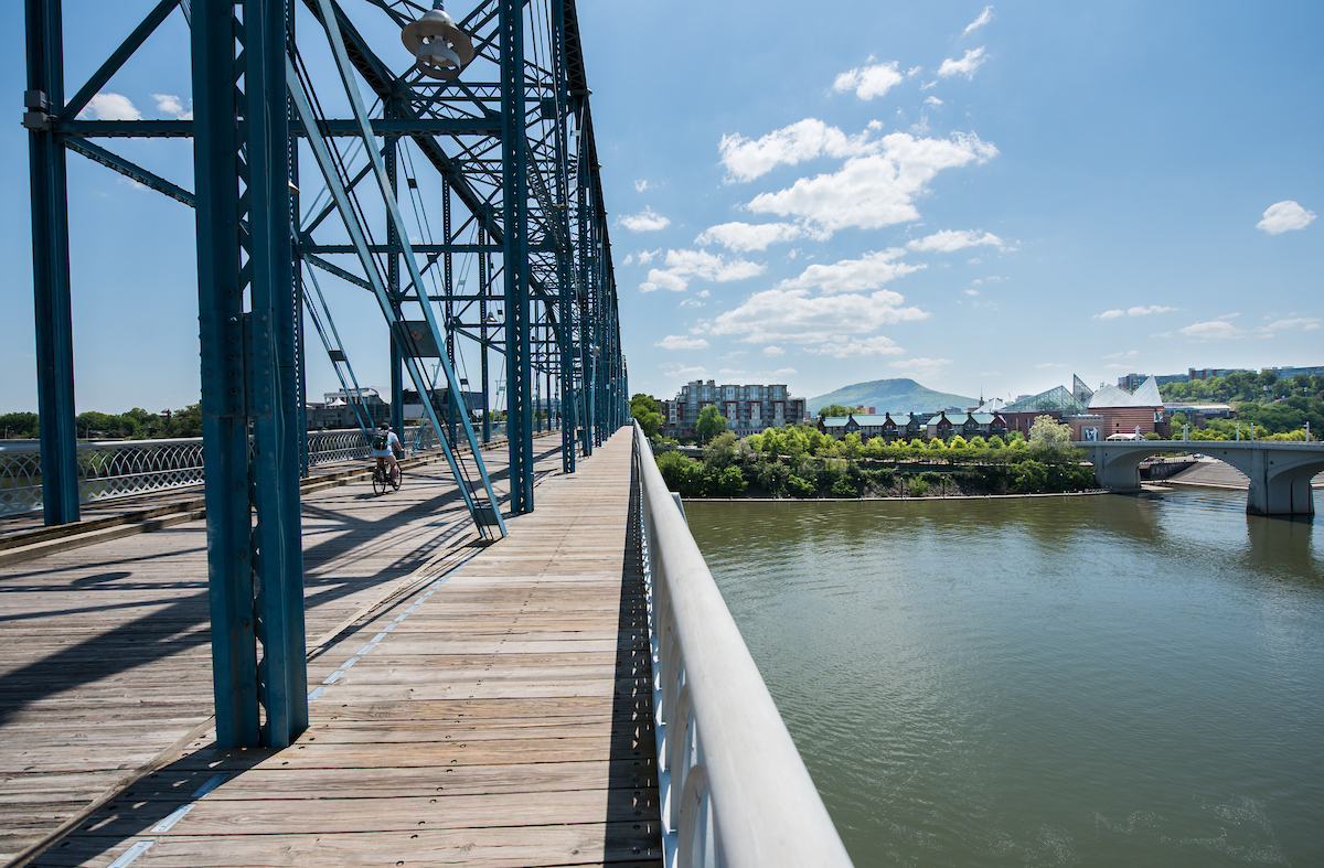 An image of the river in Chattanooga from the walking bridge and in the background downtown buildings sit in front of the far off Lookout Mountain.