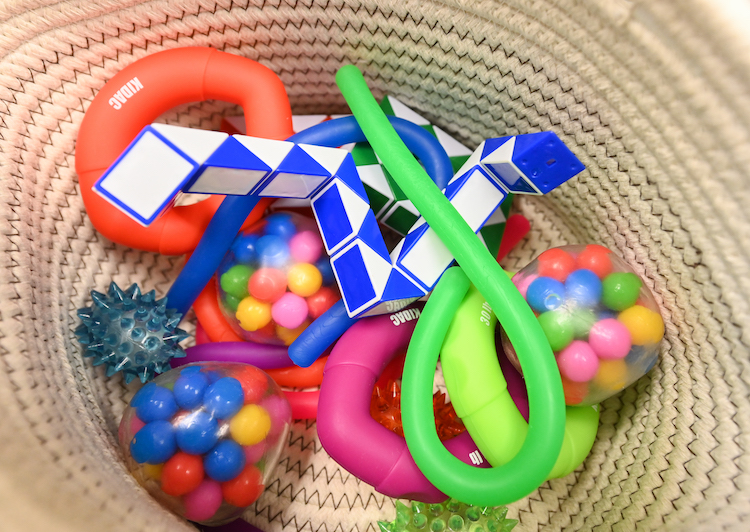 A wicker basket full of sensory brightly colored sensory toys including balls and blocks.