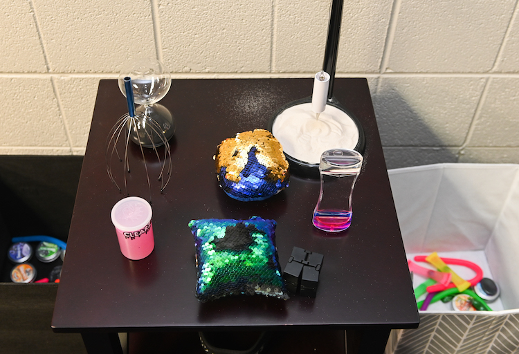 Sensory tools and items sit on a black table, including a head scratcher and putty.