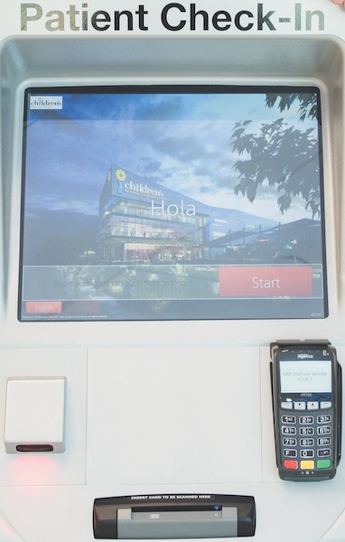 A kiosk with an image of Erlanger Childrens Hospital. Text at the top of the machine says "Patient Check-In" and a card reader sits below the screen.